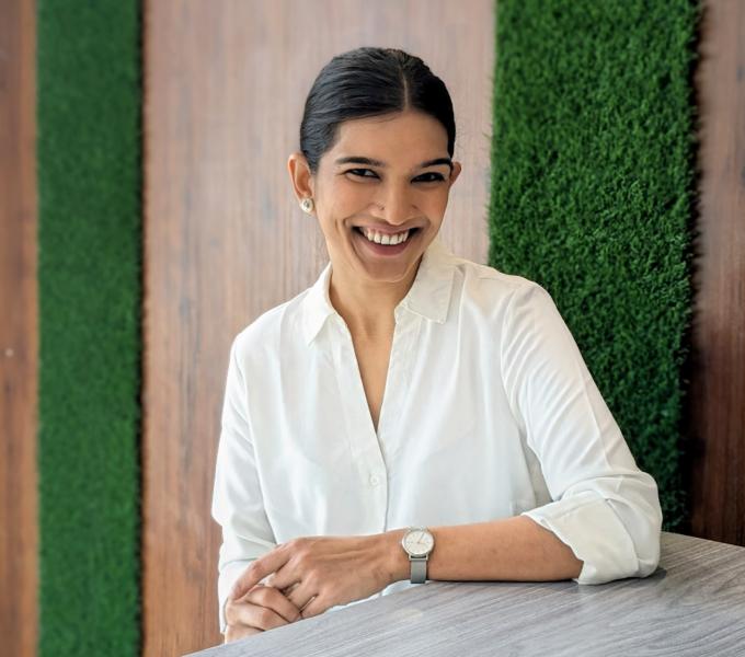 Mukherjee headshot, white shirt sitting at a table